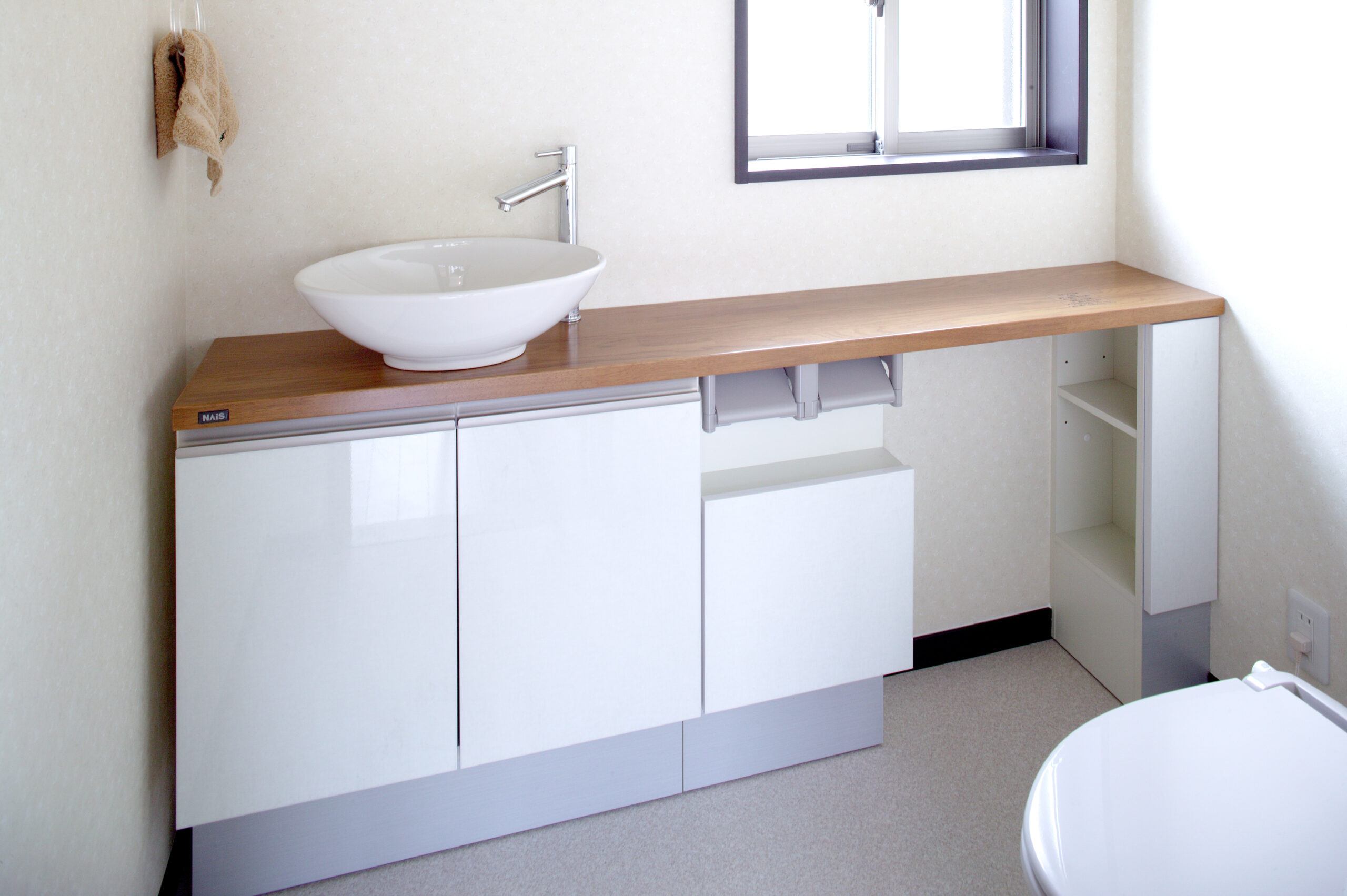 木製カウンターの洗面台とトイレが並ぶ明るい水回り空間
