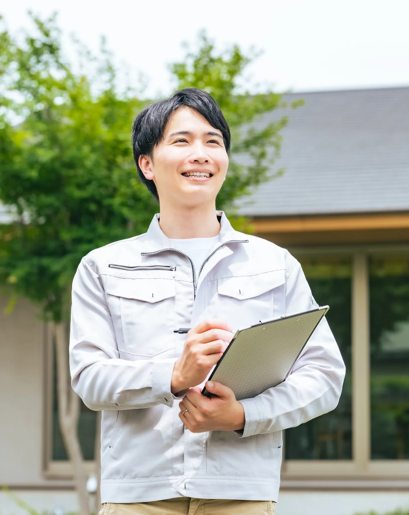 クリップボードを持ち住宅の前に立つ現地調査担当のスタッフ